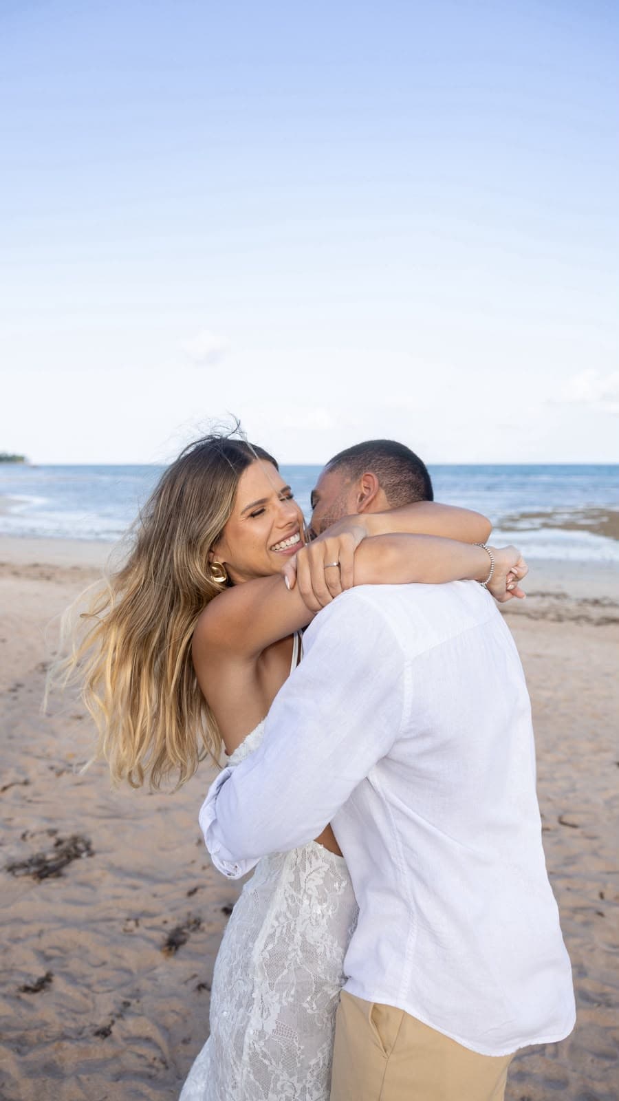 Camila abraça Victor, sorrindo, na beira da praia