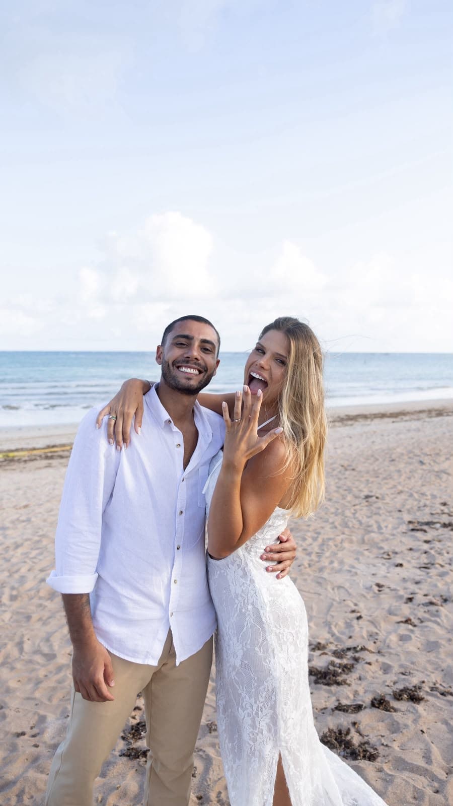 Casal sorrindo na praia, Camila mostrando o anel