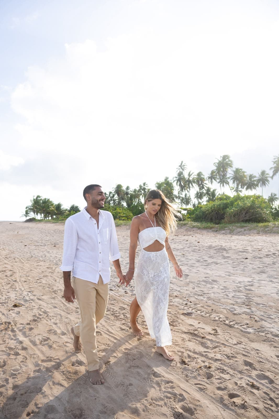 Casal caminhando de mãos dadas pela praia
